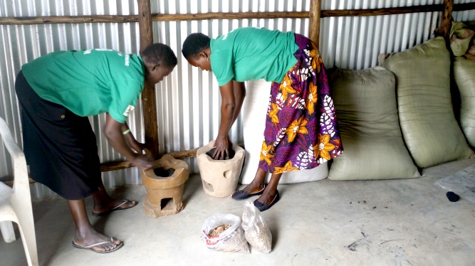 Mary Ajonye right the chairperson of Loketa women Group in experiementing how Charcoal Briquettes work in locally made energy saving stoves Photo By Robert Ariaka 1