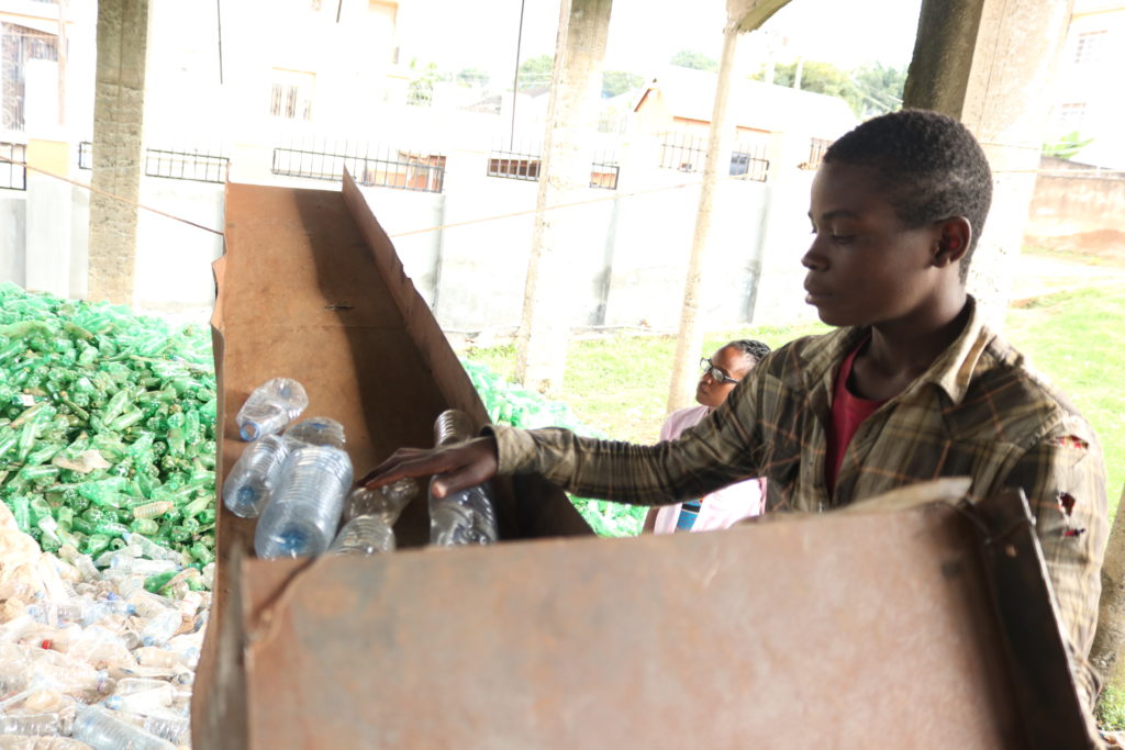Patrick Chemonges one of the team members feeds empty plastic water bottles into the chrushing machine