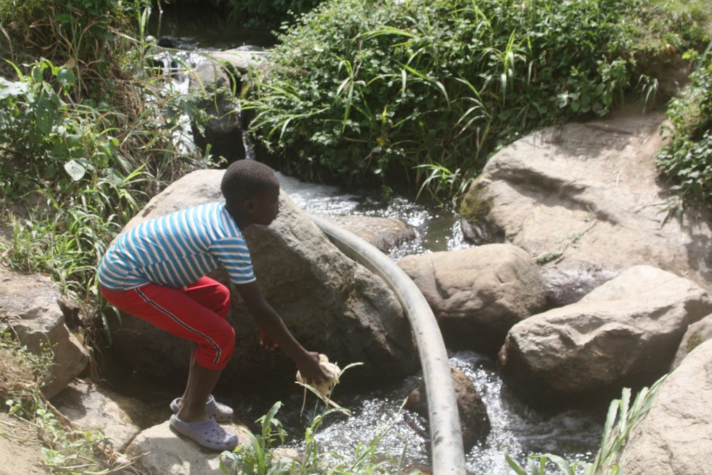 A child dumps waste in river Mpanga in Karangura in Kabarole district Uganda. Photo by Felix Basiime