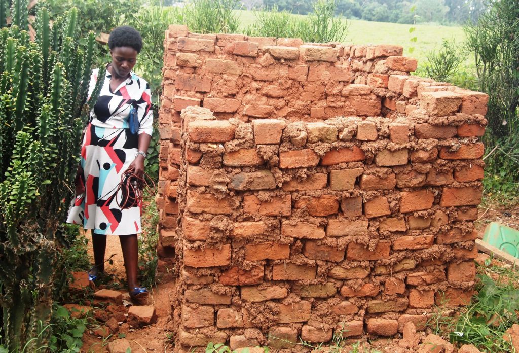 Kabarole District Health Inspector Ms Olive Tumuhairwe inspecting one of the sub standard latrine facilities. Photo by Felix Basiime