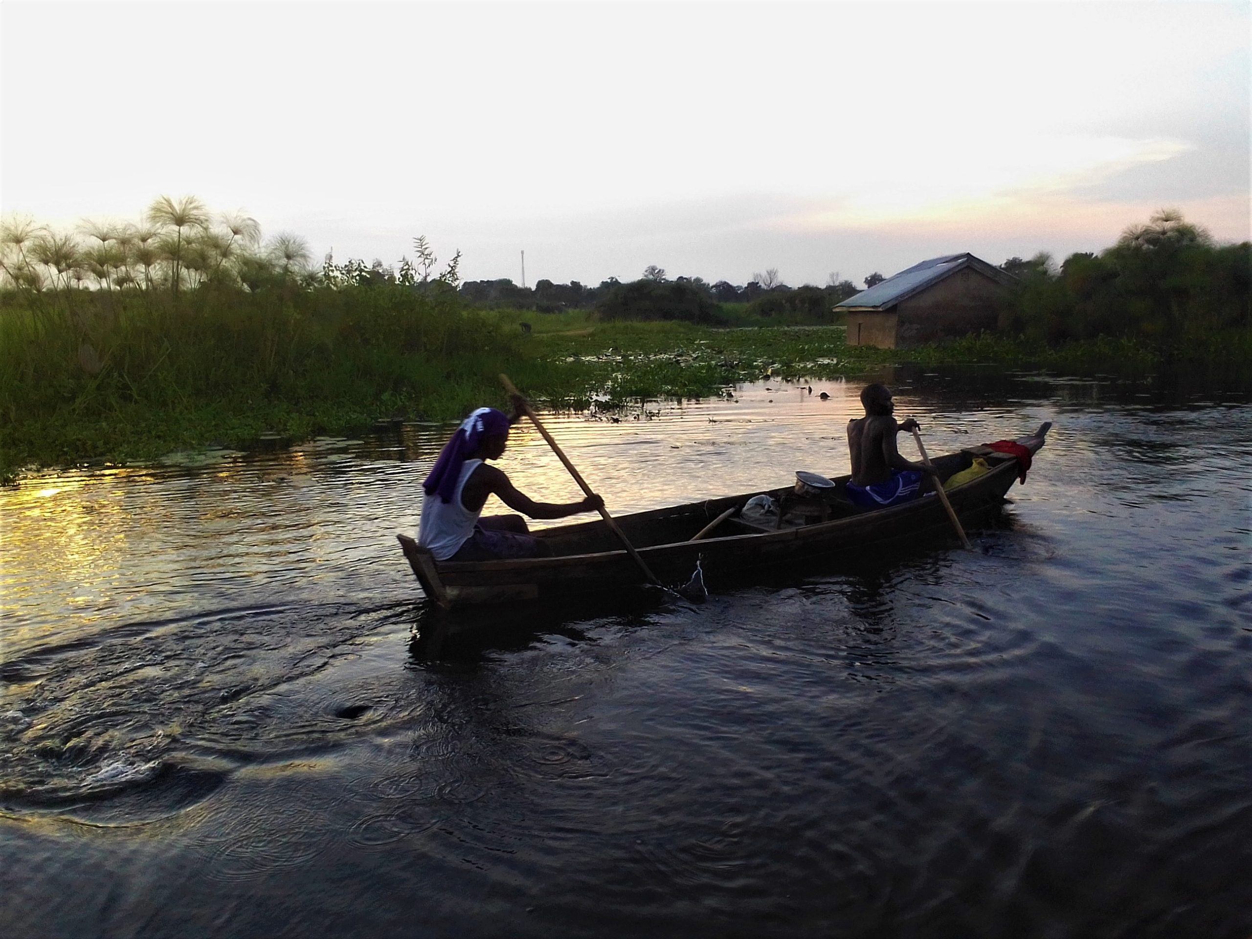 Fishermen rowing a canoe in flood waters on what used to be a compound of a house submerged in water 1 scaled