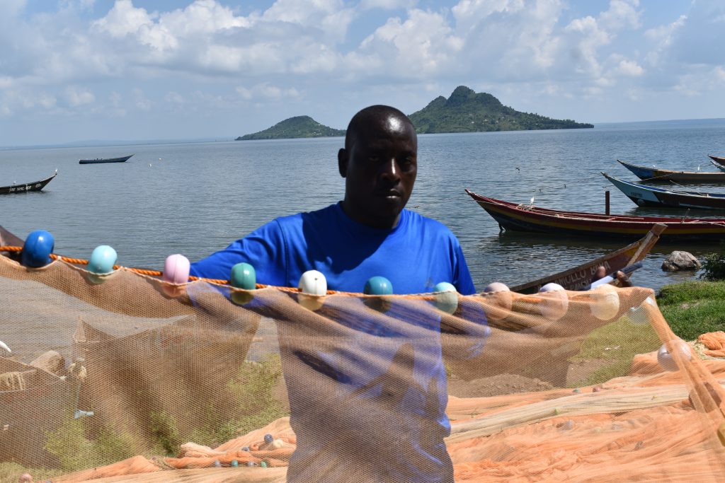 Wasungu Okeyo Assistant Chairman patrol Kiumba beach BMU displaying net used for fishing dagaa