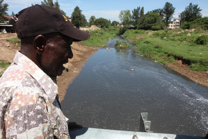A man stares at polluted River Auji that drains into Lake Victoria