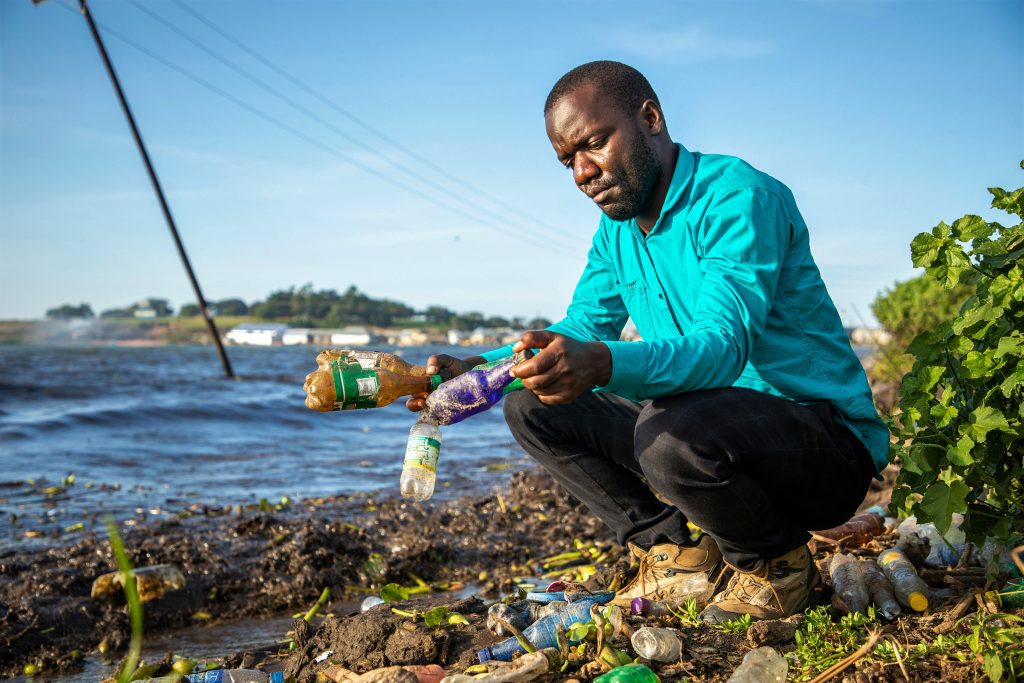 Daniel Kayemba displaying different types of plastic bottles at Malembo landingsite